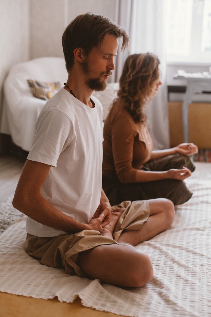 about-img-01 A man and woman meditating indoors, capturing tranquility and mindfulness.
