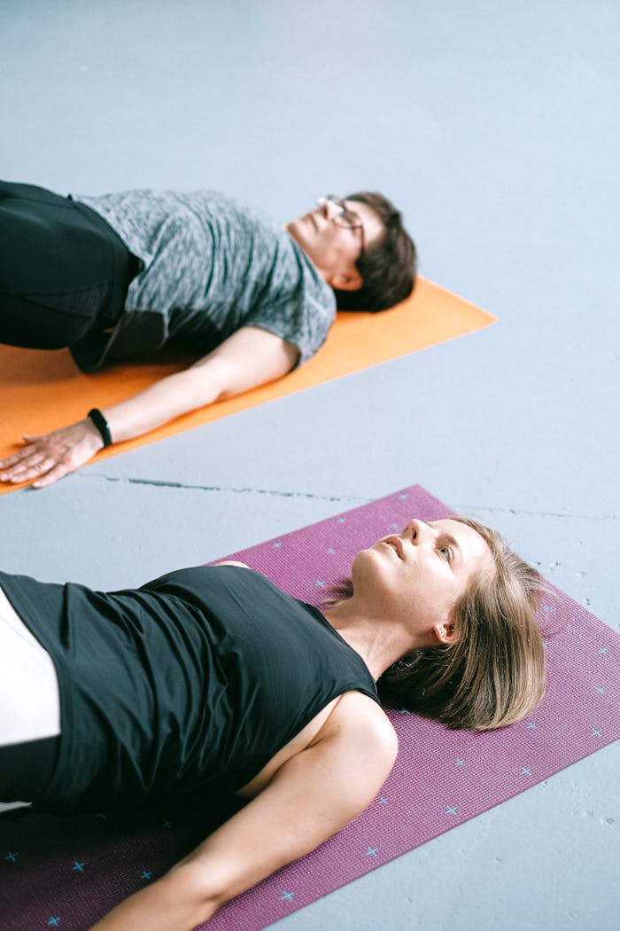 gallery-02 Two women practicing yoga poses on colorful mats in a studio setting, promoting a healthy lifestyle.